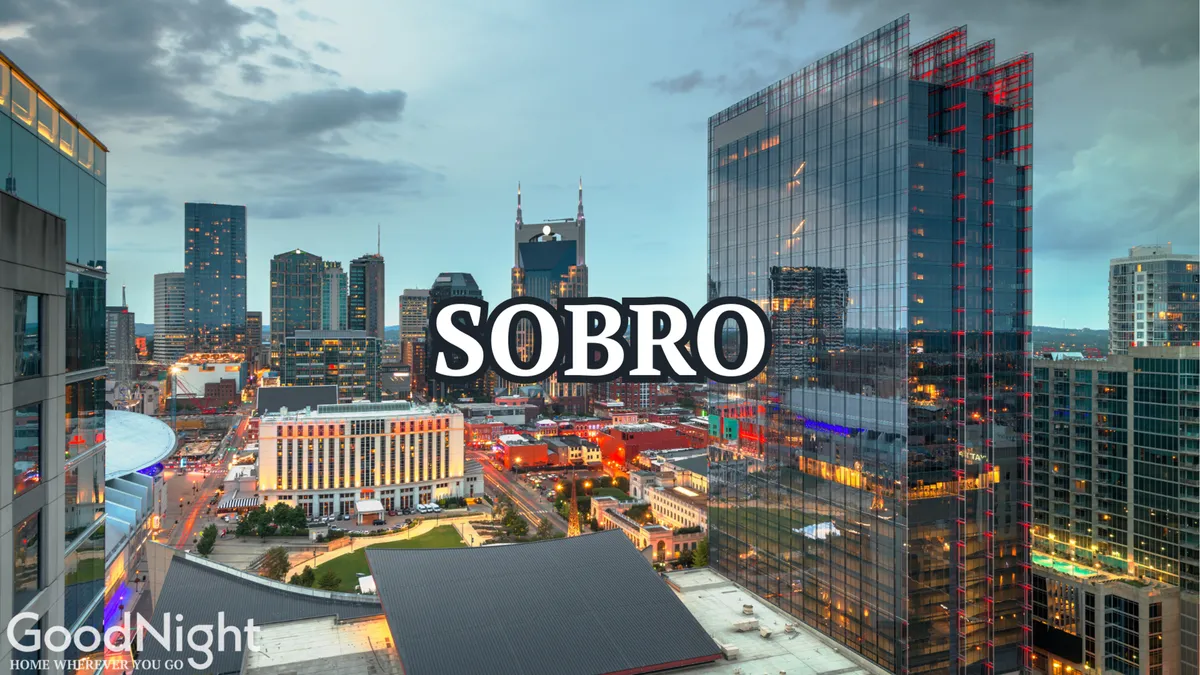 A dynamic view of the Nashville city skyline at dusk, with illuminated buildings and a riverfront area that hints at the city’s energetic nightlife and event-driven atmosphere.