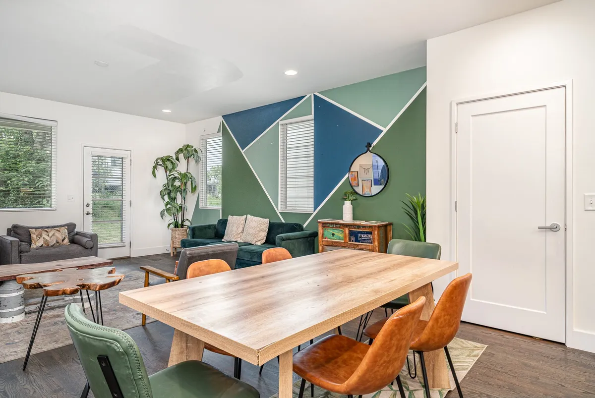 A bright dining area featuring a dining table set against a colorful accent wall, with adjacent sofa seating. The space is arranged to foster group meals, game nights, and relaxing moments, capturing the essence of communal dining and togetherness highlighted in the section.